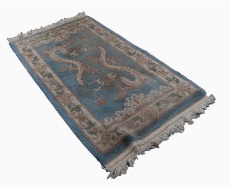 WORKED CHINESE RUG, with an embossed design in cream and brown of two dragons and sea creatures and wave pattern ends, on a s
