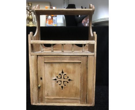 A Victorian stripped pine hanging cupboard with upper shelf, the single door pierced with a Gothic cross motif, 62 cm high 