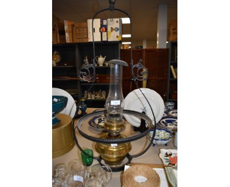 A large vintage brass oil or paraffin lamp with a cast metal ceiling mount.