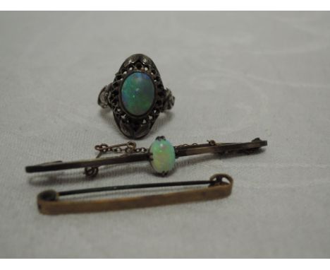 A 9ct bar brooch having a central opal, a yellow metal bar brooch stamped 9ct and a white metal dress ring having an oval opa