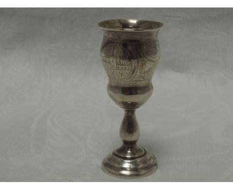 A small Russian silver vodka goblet having scenic engraving with baluster stem to stepped circular base, bearing worn Russian