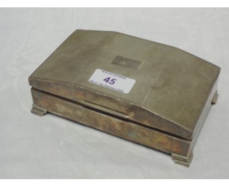 A silver cigarette box having bracket feet and engine turned decoration to raised lid, Birmingham 1960, Harman Brothers