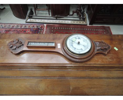 An Edwardian oak frame aneroid banjo barometer having thermometer scale and carved applique 