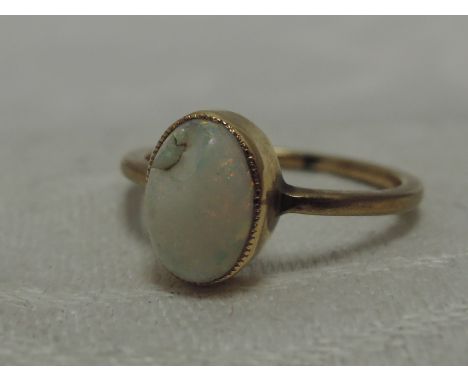 A lady's dress ring having an oval opal in a collared mount on a yellow metal loop stamped 9ct,  size O, (AF)