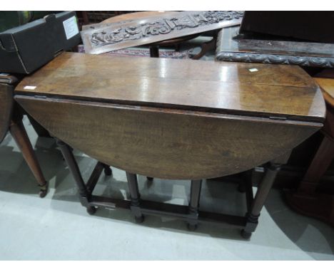 A 19th Century oak dining table having circular drop leaf top on turned gate legs