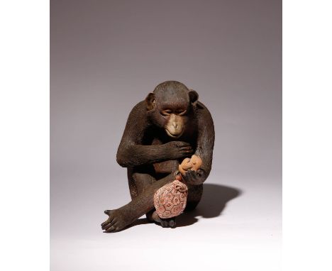 A JAPANESE POTTERY OKIMONO OF A MONKEY MEIJI ERA, 19TH CENTURY The seated primate is depicted holding a netsuke of a monkey a