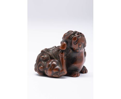 A LARGE BOXWOOD NETSUKE OF A SHISHI EDO OR MEIJI, 19TH CENTURY The lion dog depicted seated on its haunches, scratching its r