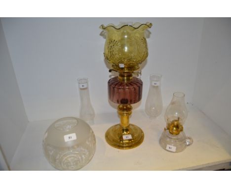 An early 20th century oil lamp, amethyst  glass reservoir, brass column;  a clear glass chamber lamp;  chimney;  etc (5)