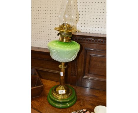 An early 20th century oil lamp, green flash milk glass reservoir, brass column