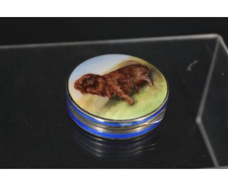 A silver and enamel circular pill box, blue enamel banding to side with enamelled dog to top, stamped Sterling (small losses 