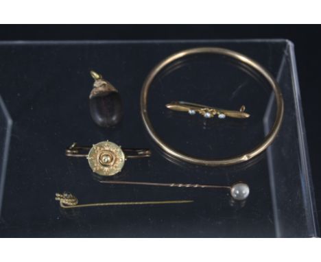 A mixed lot including a 9ct gold bangle, 9ct gold bar brooch, yellow metal stick pins including one set with moonstone etc