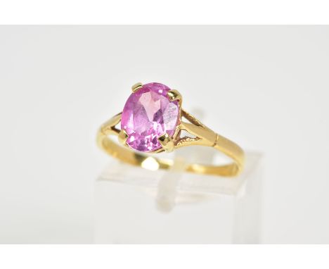 AN 18CT GOLD SAPPHIRE RING, designed with a single claw set oval cut pink sapphire to the trifurcated shoulders an plain poli