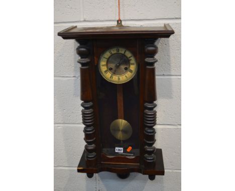 AN EARLY 20TH CENTURY SMALL VIENNA WALL CLOCK with a enamel and brass face behind a glazed door flanked by turned columns (no