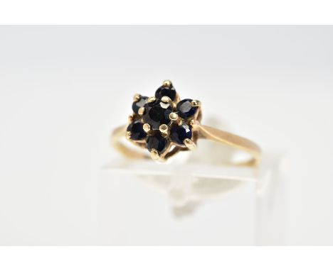 A 9CT GOLD SAPPHIRE CLUSTER RING, the tiered cluster set with circular cut sapphires, to the tapered shoulders and plain poli