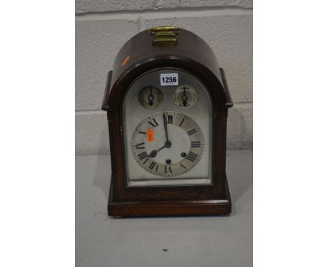 AN EARLY 20TH CENTURY OAK ARCHED TOP BRACKET CLOCK with silvered dial, pendulum and winding key, 24cm wide x 18cm deep x 34cm