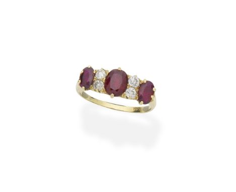 Ruby and diamond ringSet with three oval-cut rubies, with diamond accents between, the gallery of carved scrollwork design,  