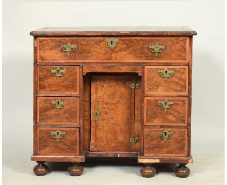 An 18c figured walnut veneered kneehole desk of rectangular form, the upper section with moulded edge and shaped corners, ove