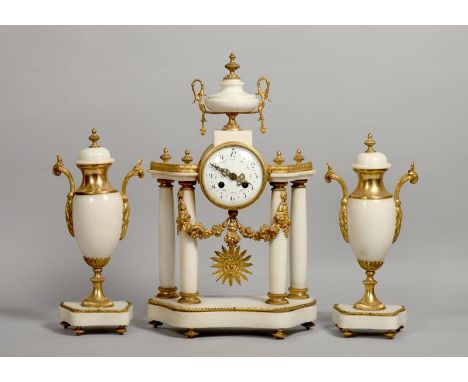 A late 19c French garniture de cheminee consisting of a columned mantel clock and two flanking urns in white marble with gilt