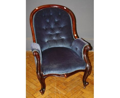 A Victorian walnut framed, deep blue button velour upholstered spoon back salon armchair, with serpentine fronted overstuffed