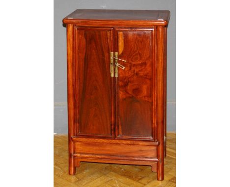 A 20th century Chinese rosewood side cabinet, the rectangular top above a pair of doors with brass lock and handles enclosing