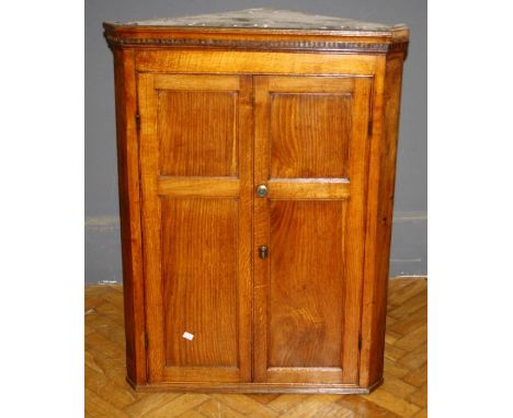 A late George III oak hanging corner cupboard enclosed by a fielded panel door H 107cm another similar George III oak hanging