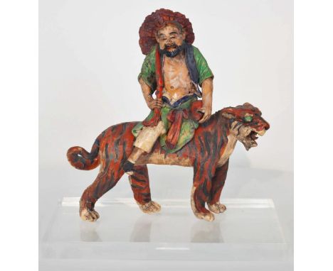 Bearded figure sitting on tiger. Ceramic tiles such as this one have been placed on Chinese temple roofs for centuries to war