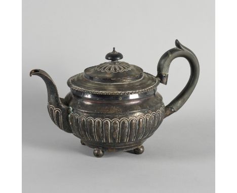 A GEORGE III SILVER TEAPOTOf compressed circular form with partly fluted decoration, with black fittings, raised on four bun 