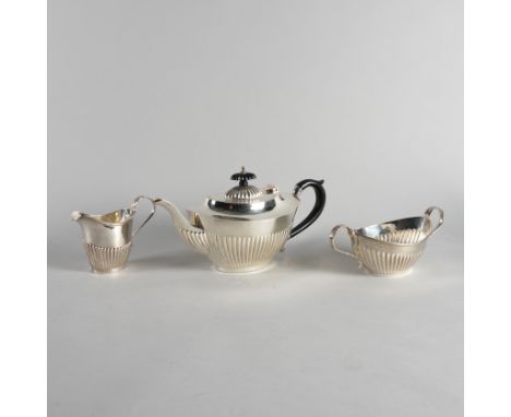 A SILVER THREE PIECE TEA SETComprising; a teapot with black fittings, a twin handled sugar bowl and a milk jug, each piece of