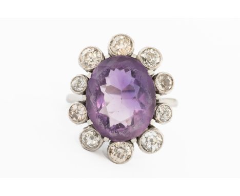 A WHITE GOLD, AMETHYST AND DIAMOND OVAL CLUSTER RINGClaw set with the oval cut amethyst at the centre, within a surround of t