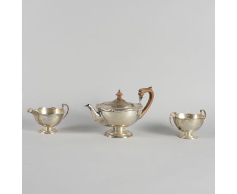 A SILVER THREE PIECE TEA SETComprising; a teapot with wooden fittings, a twin handled sugar bowl and a milk jug, Birmingham 1