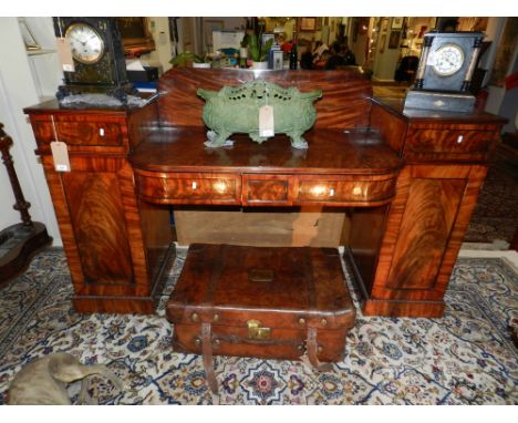 A George IV mahogany bow front pedestal sideboard the centre section with raised back in cooperating apron drawers, the pedes