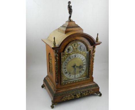 An early 20th century German oak mantel clock, the arched brass dial having silvered chapter ring with Arabic and Roman numer