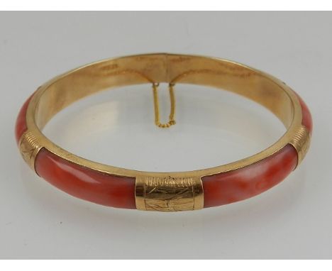 A yellow metal and coral mounted bangle bracelet, having engraved decoration, the clasp stamped 14k.