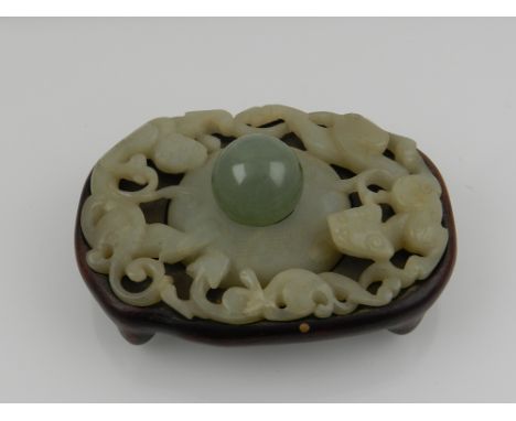 A 19th century Chinese green jade carved and pierced plaque, raised on hardwood stand, together with a jade ball. (2)