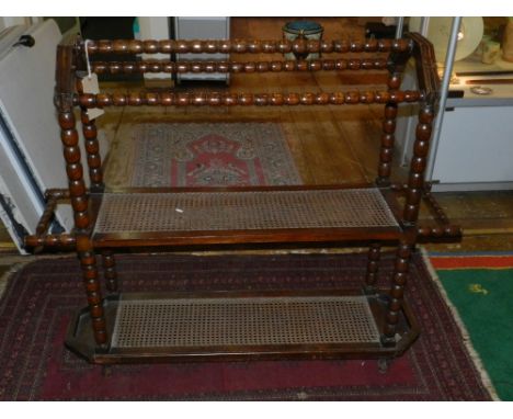 An early 20th century walnut boot rack, with cane tiers and bobbin turned supports, W. 135cm
