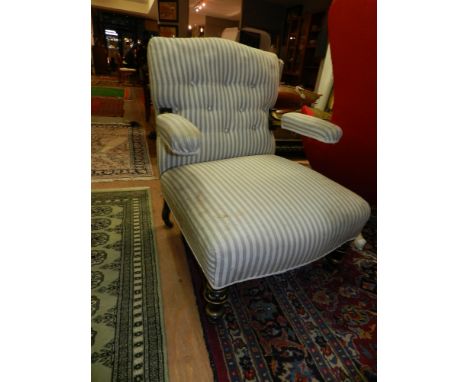 A Victorian button-back upholstered ebonised and giltwood armchair, having cream and grey striped fabric, the open arms incor