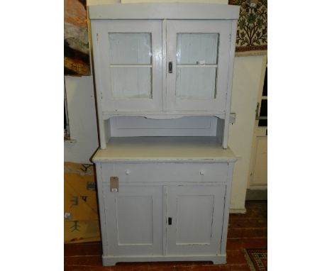 An early 20th century light grey painted cabinet, the upper section with glazed panel doors above a recess and pair of panel 