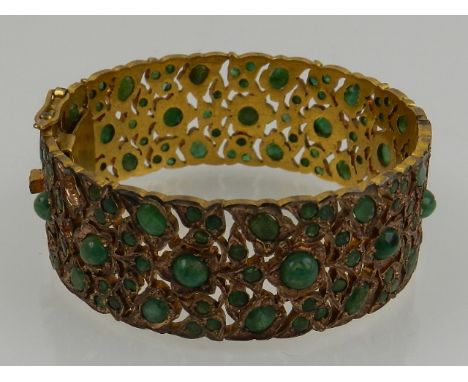 An unusual brass and emerald openwork bangle bracelet, set faceted and cabouchon stones, 