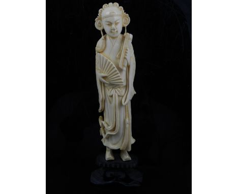 A fine 19th century Chinese ivory tall standing carved figure of a religious scholar, holding a fan in one hand and a scroll 