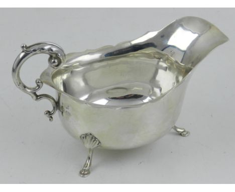 A silver sauceboat, having waved rim, raised on tripod feet, hallmarked Birmingham. 