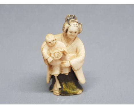 An early 20th century carved netsuke of a mother and child, signed.