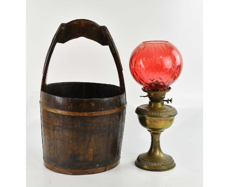 A Chinese metal bound water bucket, height 58cm, and a brass oil lamp with cranberry shade (2). 