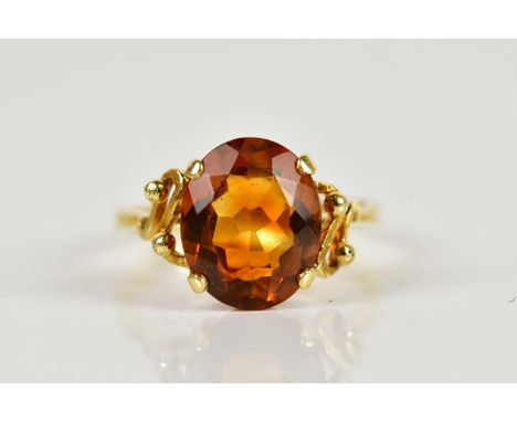 An 18ct yellow gold citrine dress ring, with scroll detail to the shoulders and oval cut stone, size R, approx 4.8g.