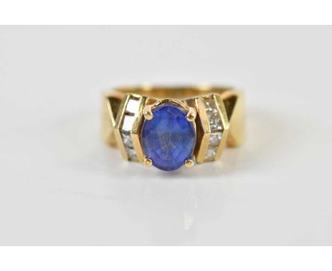 A 14ct tanzanite dress ring, the oval four claw set stone flanked by eight princess cut diamonds in angled mounts to the shou
