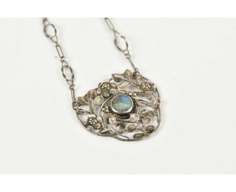 A white metal pendant on chain in the Arts and Crafts style, with foil backed enclosed opal to the centre of the pierced pend