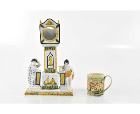 A pearlware watch stand modelled as a longcase clock between two figures, height 26cm, with a Wheeldon mug (2)Condition Repor