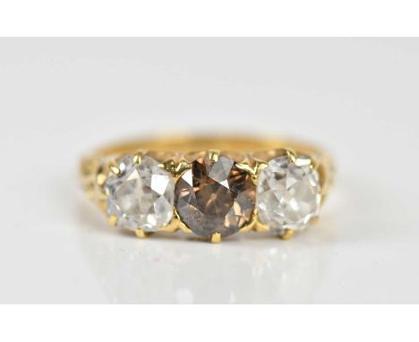 A yellow metal three stone diamond ring with certified central fancy deep brown natural stone weighing 0.73 carats graded SI,