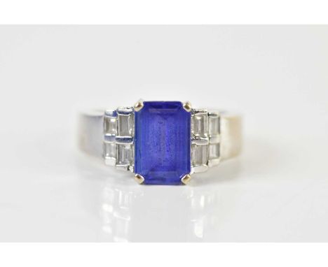 A 14ct white gold tanzanite and diamond stepped ring, with emerald cut four claw central tanzanite and four baguette cut diam