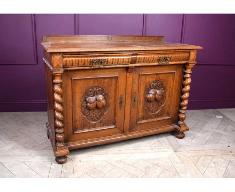 A late 19th century French light oak dresser base, with two drawers and two carved cupboard doors decorated with fruit and le