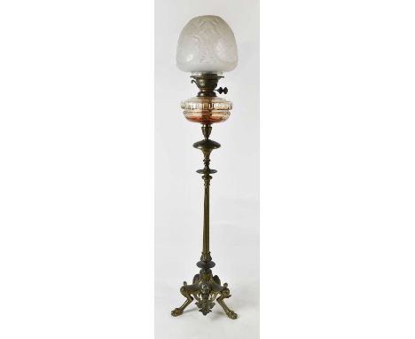 A 19th century bronze oil lamp with cut glass reservoir and moulded glass shade, the triangular shaped base with mounted mask